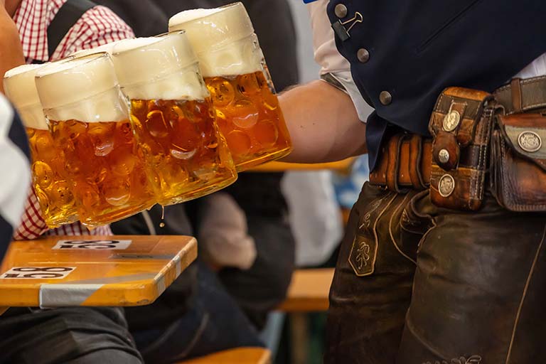 Komm ins Festzelt-Team! Wir suchen in Voll- und Teilzeit Servicekräfte, Schankpersonal, Köche und Küchenhilfen (m,w,d) Bild eines Kellners beim bedienen im Bierzelt